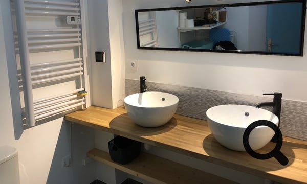 La salle de douche avec double vasques, wc, machine à laver, sèche linge et sèche cheveux